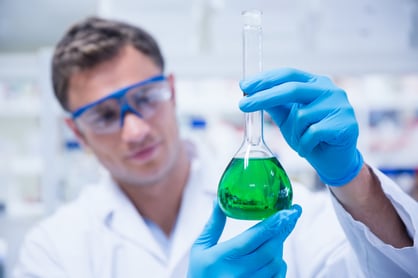 Chemist examining beaker of green chemical in the laboratory